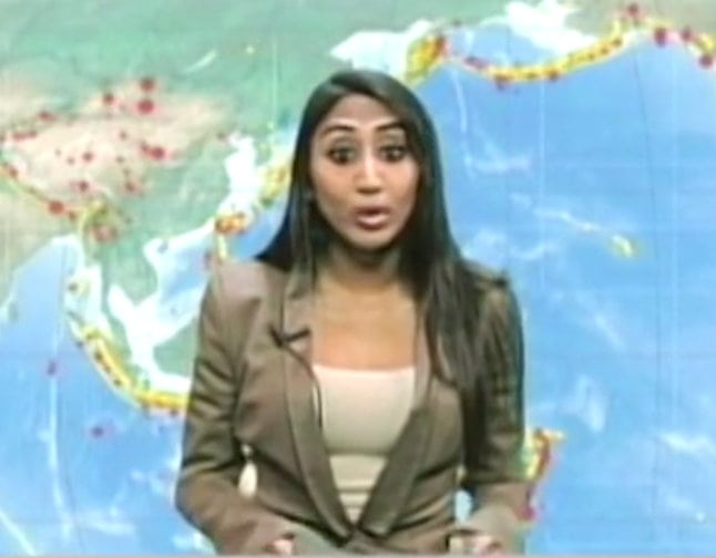 Geetha presenting a news broadcast in front of a world map